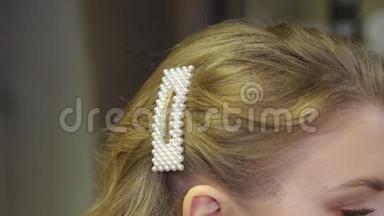 专业的理发师把发夹放在女孩的头上。
